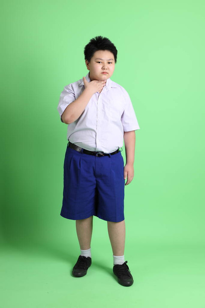 The Asian boy with student uniform on the green background. - Zdjęcie, obraz