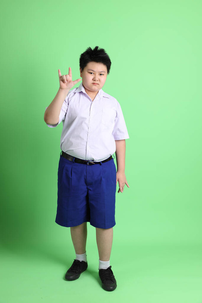 The Asian boy with student uniform on the green background. - Φωτογραφία, εικόνα