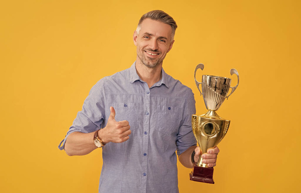 happy man hold golden cup and show thumb up, success. - Фото, изображение