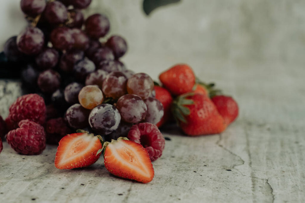 Appetizing, fresh, juicy, ripe grape, raspberry and strawberry assortment on light gray background.Excellent image for dessert banners and advertisements. Greeting card. Post card. Place for your text. - Photo, Image