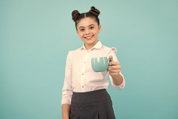 Teenage girl with cup of cappuccino coffee or tea. Child with cup on blue background, morning drink beverage - Photo, Image