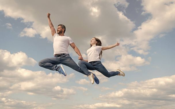 幸せな父親と娘が空を飛び跳ねる。家族の日. - 写真・画像
