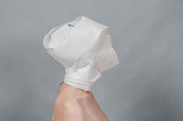 Γυμνό γυναικείο σώμα σε προφίλ. Το κεφάλι είναι τυλιγμένο σε λευκό χαρτί. Έννοια απειλής - Φωτογραφία, εικόνα