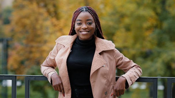 Happy joyful young african american woman standing in autumn park attractive stylish confident successful businesswoman looking at camera smiling healthy white teeth beautiful model posing outdoors - Photo, Image