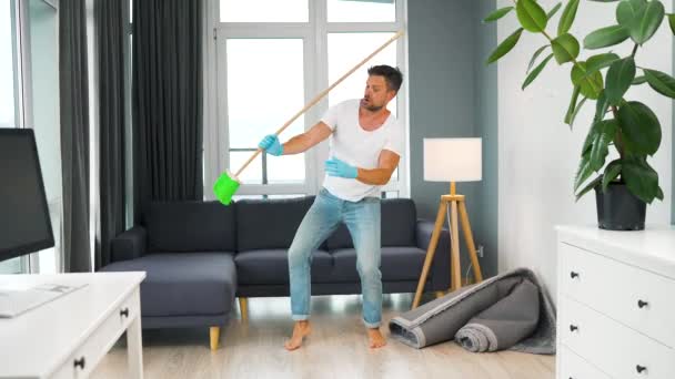 Caucasian man cleaning the house and having fun with a broom. Slow motion - Video