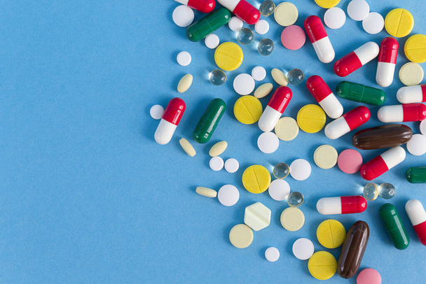 Background of multi-colored pills on a blue background - Foto, Imagem