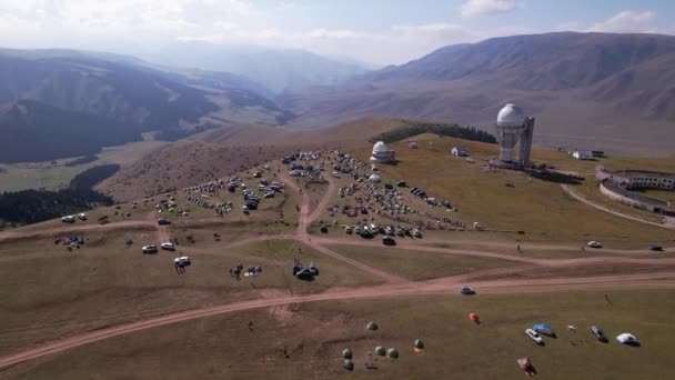 The Assy-Turgen Observatory with a large telescope. A tent camp is located nearby. There are colored tents, cars and people are resting. Big clouds over green hills. Two domes for studying the stars - Materiaali, video