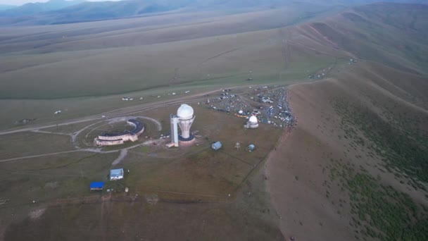 Two large telescope domes at sunset. Drone view of Assy-Turgen Observatory. Beautiful red sunset. Green hills and clouds. Tourists watch the sun. There is a large tent camp and cars nearby. Kazakhstan - Video, Çekim