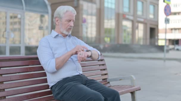 Senior Old Man Περιήγηση στο Internet για Smartphone, ενώ κάθεται σε εξωτερικούς χώρους για Bench - Πλάνα, βίντεο
