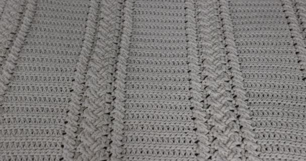 Surface of a crochet blanket with intertwined braids finished in beige cotton thread, over putting another white blanket on top, embossed stitch pattern. Handmade craft creativity - Felvétel, videó