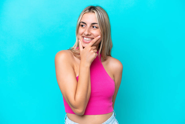 Young caucasian woman isolated on blue background looking to the side and smiling - Foto, immagini