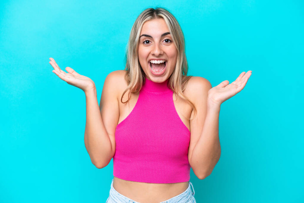 Young caucasian woman isolated on blue background with shocked facial expression - Foto, imagen