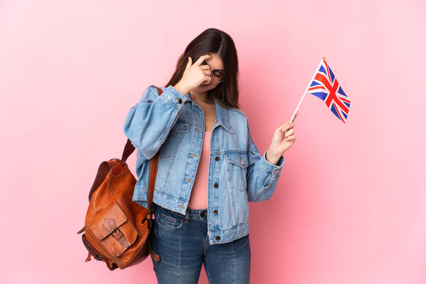 Mujer joven sosteniendo una bandera del Reino Unido aislada sobre fondo rosa riendo - Foto, Imagen