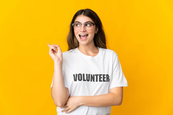 Young volunteer woman isolated on yellow background intending to realizes the solution while lifting a finger up - Foto, immagini