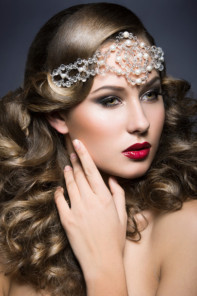 Beautiful woman with evening make-up and curls and big jewelry on her head. Beauty face. - Fotó, kép