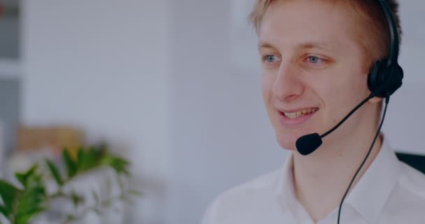 Young man doing video meeting using headset talking. Businessman working online, talking with client. Man working at helpdesk support, remote work, home office. - Video, Çekim