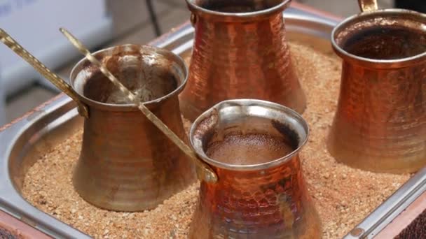 Four copper coffee turks brew Turkish coffee on the sand. - Séquence, vidéo