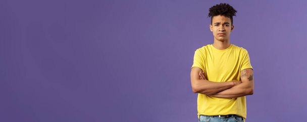 Close-up portrait of skeptical, unimpressed young man with dreads, look judgemental and uninterested, cross arms chest, go on impress me, smirk disappointed, purple background. - Photo, Image