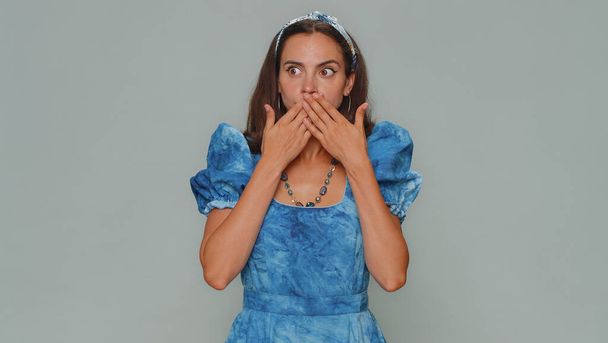 I will not say anyone. Frightened young woman closing her mouth with hand, looking intimidated scared at camera, gestures no, refusing to tell terrible secret, unbelievable truth. Adult female girl - Foto, imagen