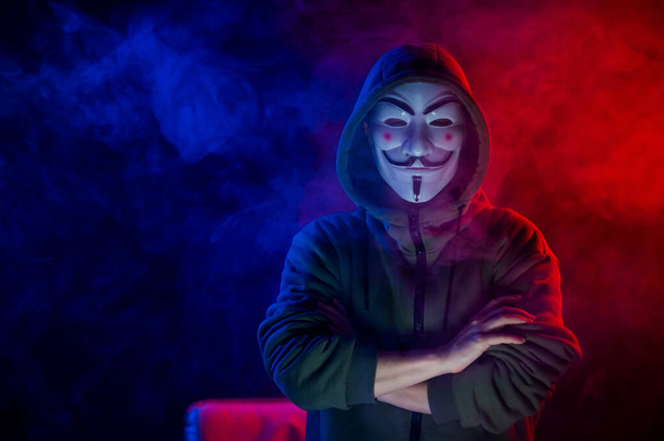 June 5, 2022 Novosibirsk, Russia: Hooded portrait of Anonymous in the dark in red-blue smoke - Photo, Image