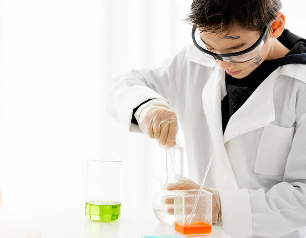 School boy doing chemistry experiment measuring chemical liquids in elementary science class. Clever pupil analyzing results of test in lab - Foto, Imagem