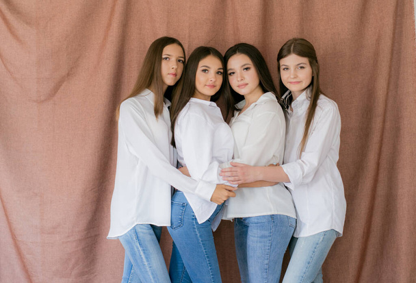 Pretty teenage girls models in trendy jeans and white shirts in the studio against the  textile background . Teenage fashion. beauty and fashion - Foto, Bild