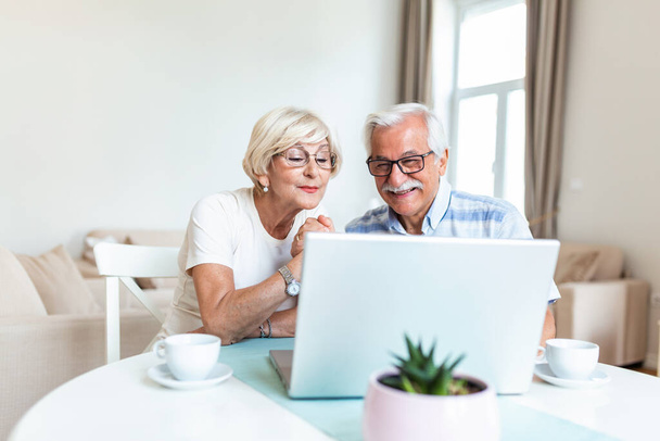 Щаслива стара сімейна пара розмовляє з друзями і сім'єю за допомогою ноутбука, здивована збуджена старша жінка, дивлячись на комп'ютер махаючи і посміхаючись
. - Фото, зображення