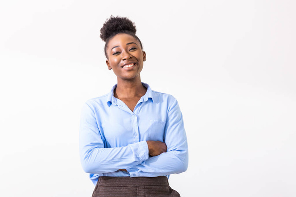 Молодая афроамериканская деловая женщина со сложенными руками стоит, смотрит в камеру, улыбается. Концепция лидера женского бизнеса - Фото, изображение