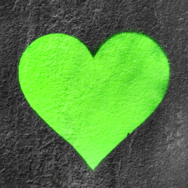 Green urban heart. Fluo love heart hand drawn on grungy wall. Textured background trendy street style. - 写真・画像