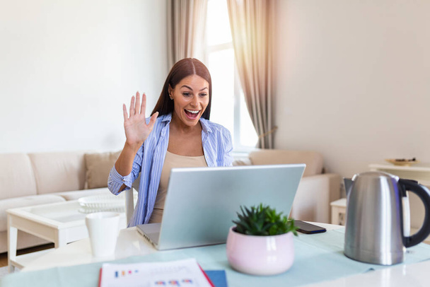 Young woman waving at laptop and talking to her friends via video call, girl student talking by video conference call, female teacher trainer tutoring by webcam, online training, e-coaching concept - Foto, Bild