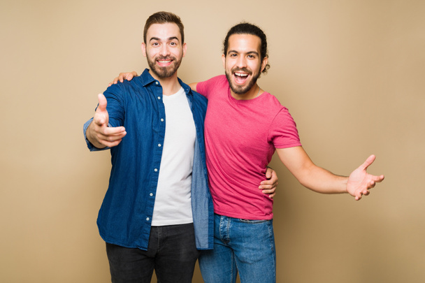 Щасливий кавказький гей чоловік і його латинський хлопець виглядають схвильованим сміхом і веселим часом на фоні студії
 - Фото, зображення