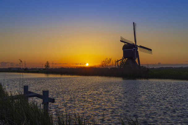 Zachód słońca z wiatrakiem Broekmolen, Molenlanden - Nieuwpoort, Holandia - Zdjęcie, obraz