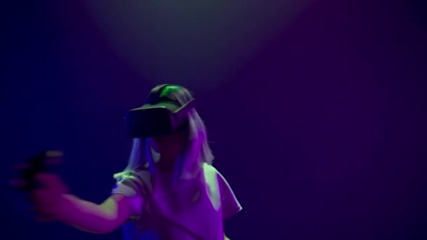 Pro gamer playing virtual reality game using invisible swords closeup. Woman wearing VR headset enjoying online videogame shooter with joysticks controllers as weapon. Cool retro neon colours room  - Video