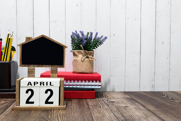 22 апреля календарная дата текст на белом деревянном блоке с канцелярскими принадлежностями на деревянном столе. Концепция даты календаря. - Фото, изображение