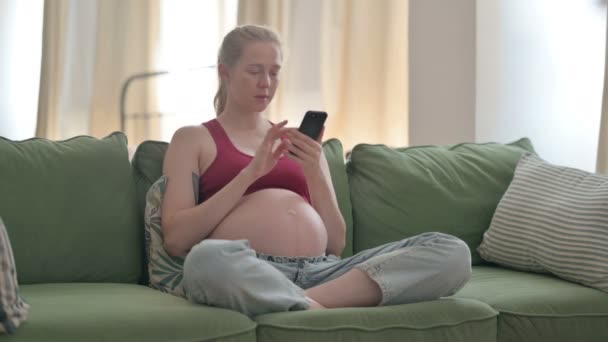 Pregnant Young Woman Using Smartphone while Sitting on Sofa - Video, Çekim