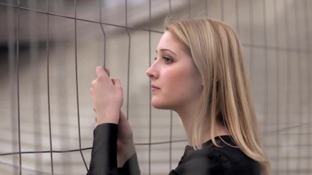 Jovem mulher triste vale a pena segurar em uma cerca de metal
 - Filmagem, Vídeo