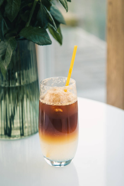 Coffee cooling drink espresso tonic in a glass with a yellow drinking straw. - Foto, afbeelding
