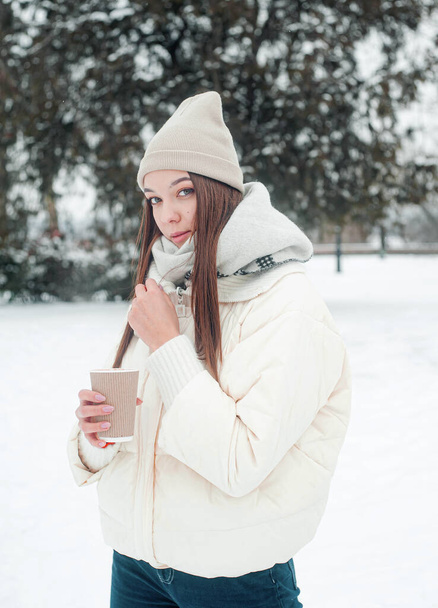 женщина в зимней одежде пьет кофе на открытом воздухе  - Фото, изображение