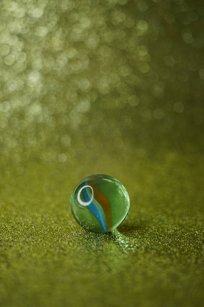 Скляна куля на блискучому золотому столі з розмитим тлом у бульбашках
. - Фото, зображення