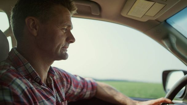 Man driving car country road closeup. Focused driver inside cabin at green eco harvest field. Successful agribusiness owner manager inspecting farmland crop in suv. Middle aged adventurer traveling. - Foto, Imagen