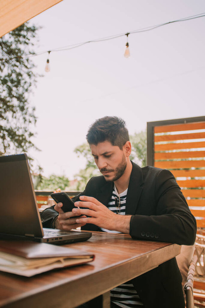 Επιχειρηματίας κοιτάζοντας το τηλέφωνό του, ενώ κάθεται στο καφέ - Φωτογραφία, εικόνα