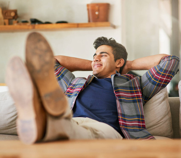 Home comforts. a handsome young man relaxing on the sofa at home - 写真・画像