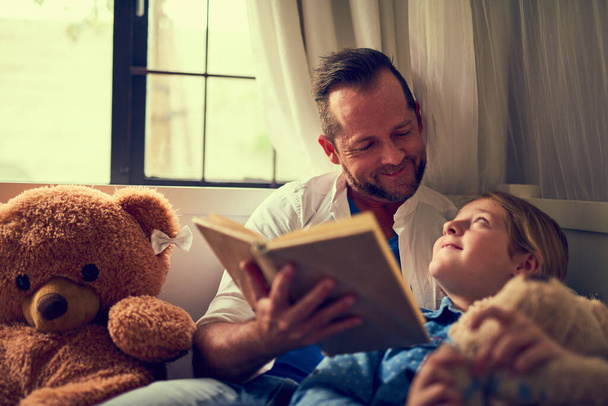 Тогда прочтем еще одну. отец читает сказку своей маленькой дочери дома - Фото, изображение