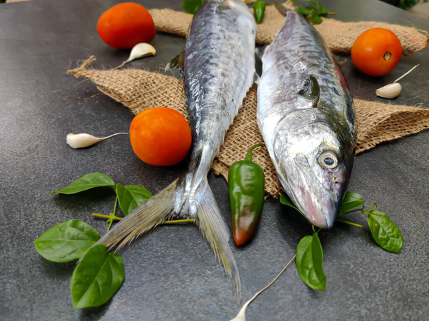 Selectieve Focus van Vers Ziener Vis, Koning Vis versierd met kruiden en groenten op een Zwart houten pad. - Foto, afbeelding