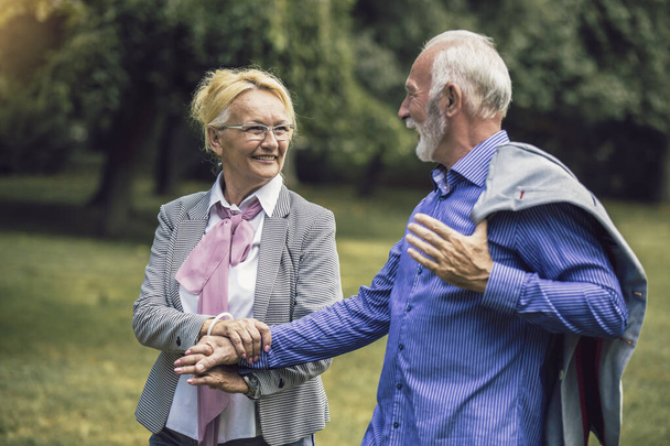 Sénior casal caucasiano ativo de mãos dadas parece feliz no parque à tarde - Foto, Imagem
