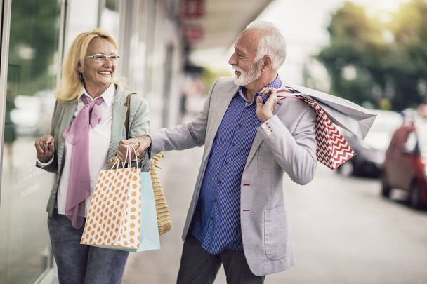 Щаслива старша пара ходить зі своїми сумками в місті
. - Фото, зображення