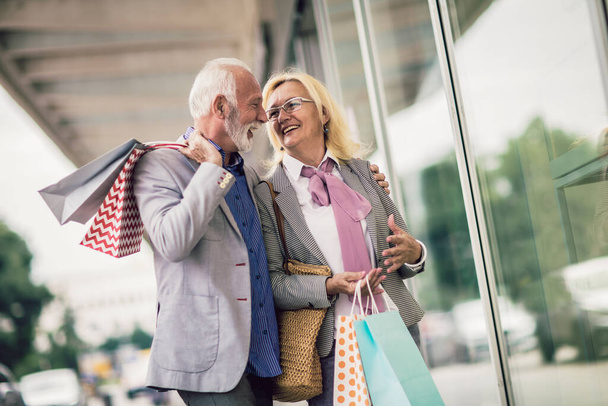 Happy senior couple walking with their shopping bags in the city. - Foto, afbeelding