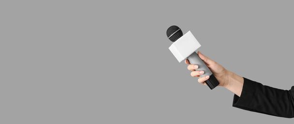 Journalist's hand holding microphone on grey background with space for text - Foto, Imagem