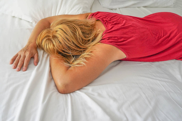 Γυναίκα με κοκκινομάλλα μαλλιά και τα χέρια στο σεντόνι του κρεβατιού. Έννοια για ένα καλό πρωινό, ύπνο, χρόνος για τον εαυτό σας. Στιγμή σεξουαλικής ευχαρίστησης ή οργασμού στο κρεβάτι. Έννοια δημιουργού φύλου - Φωτογραφία, εικόνα