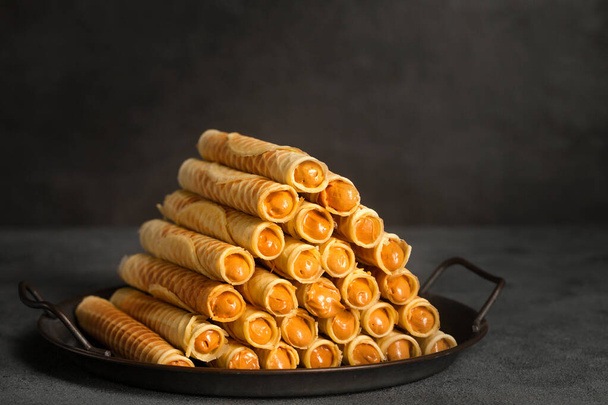 Ruddy crispy tubes with condensed milk on a metal tray - Foto, imagen